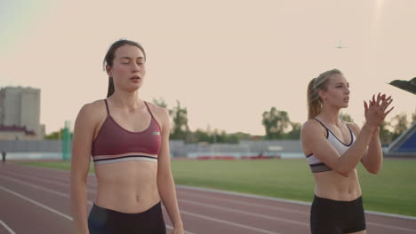 3-women-runners-prepare-for-the-long-distance-race-at-the-stadium-at-sunset-in-slow-motion